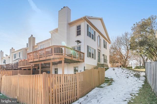 snow covered back of property with a deck