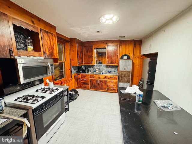 kitchen featuring decorative backsplash, black refrigerator, white range with gas cooktop, and sink