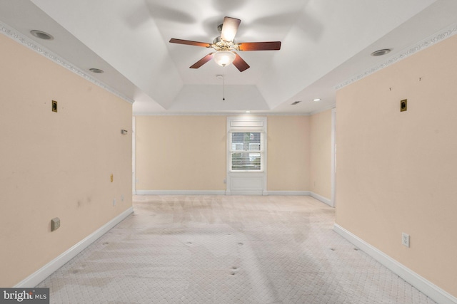 unfurnished room with ceiling fan, a tray ceiling, and light carpet