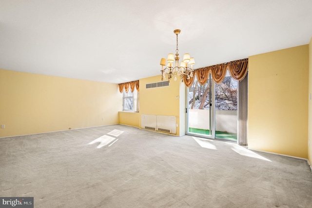 spare room with carpet flooring and a chandelier