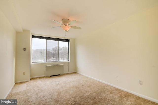 empty room featuring ceiling fan, radiator, and light colored carpet