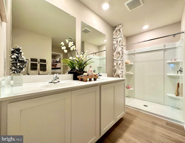 bathroom featuring hardwood / wood-style flooring, walk in shower, and vanity