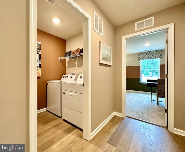 clothes washing area featuring washer and dryer and light hardwood / wood-style flooring