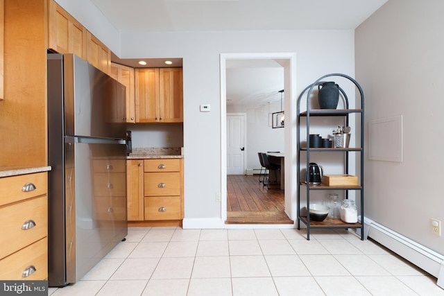 kitchen featuring light tile patterned floors, stainless steel fridge, and a baseboard heating unit