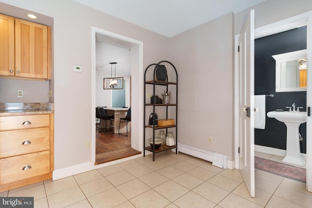 interior space featuring light tile patterned floors, baseboard heating, and sink