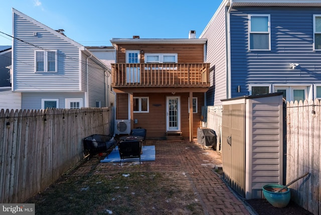 rear view of house featuring a shed, a balcony, and ac unit