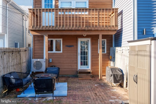 rear view of house with a balcony, ac unit, an outdoor fire pit, and a patio