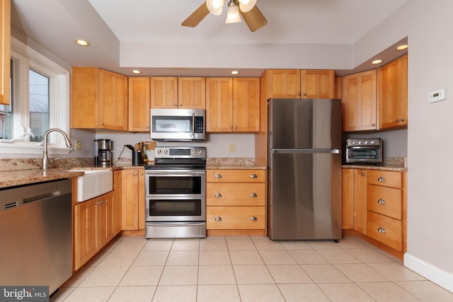 kitchen featuring light stone countertops, appliances with stainless steel finishes, sink, ceiling fan, and light tile patterned floors