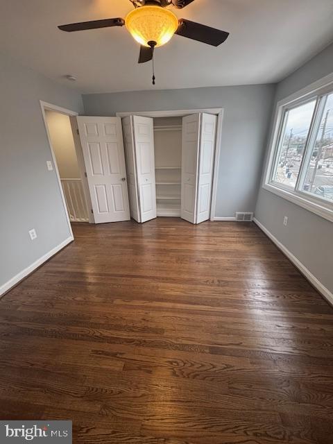 unfurnished bedroom with ceiling fan, a closet, and dark hardwood / wood-style floors