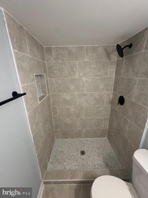 bathroom with toilet and tiled shower