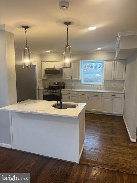 kitchen featuring hanging light fixtures, appliances with stainless steel finishes, sink, and white cabinetry