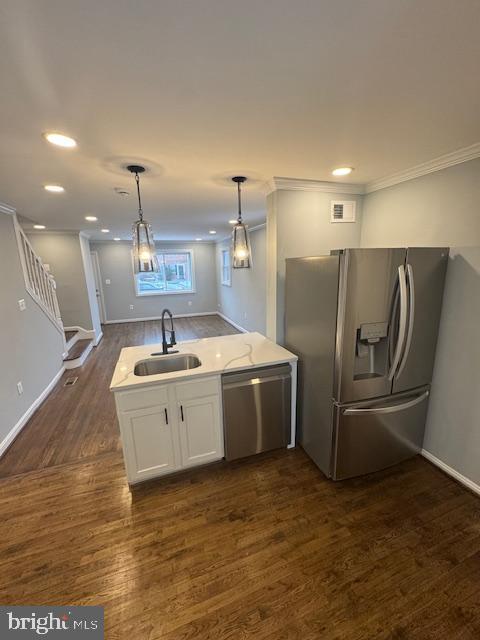 kitchen featuring decorative light fixtures, sink, white cabinetry, appliances with stainless steel finishes, and dark hardwood / wood-style flooring