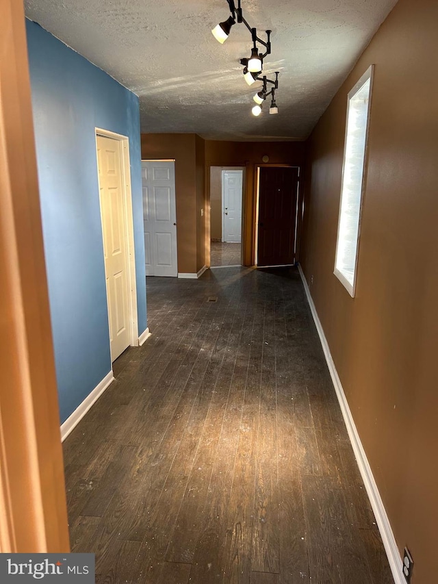 hallway featuring dark wood-type flooring and a textured ceiling