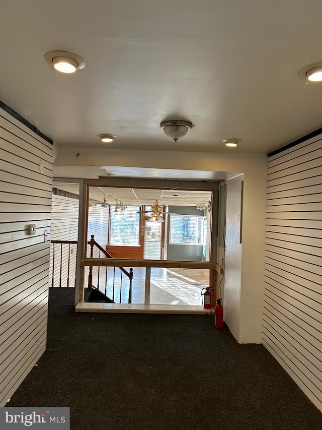 corridor featuring wood walls and carpet flooring