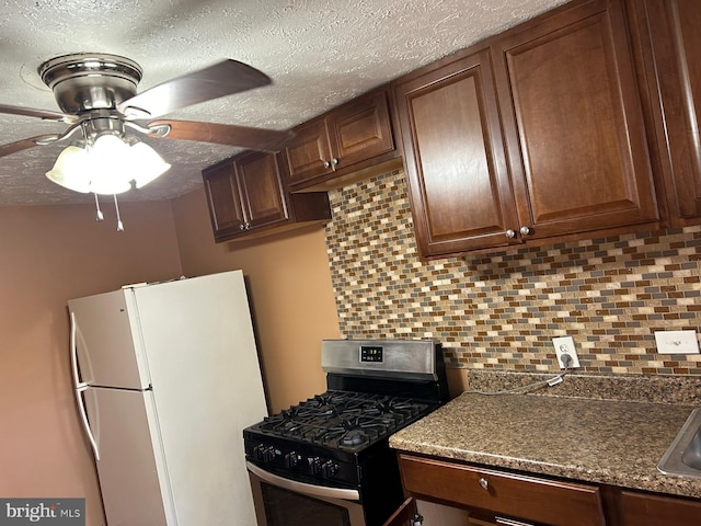 kitchen featuring gas range, white fridge, ceiling fan, and decorative backsplash