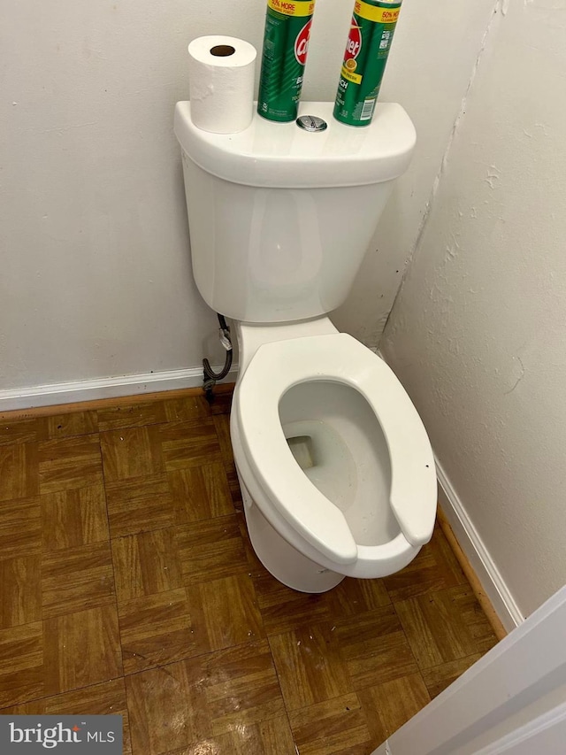 bathroom featuring parquet flooring and toilet