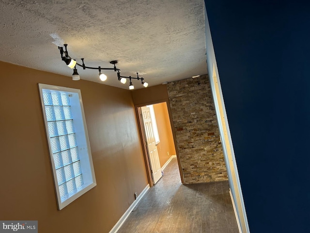 corridor with a textured ceiling, hardwood / wood-style floors, and a wealth of natural light