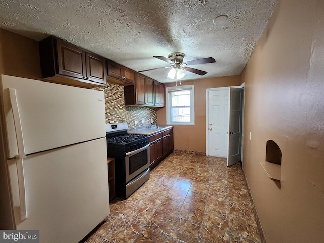 kitchen with backsplash, white refrigerator, stainless steel range with gas stovetop, and dark brown cabinets