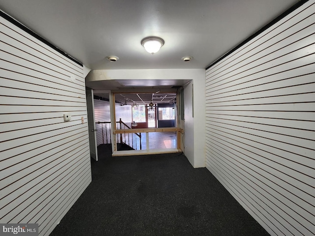 hallway featuring wood walls