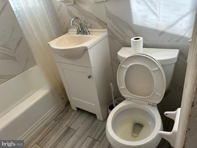 full bathroom with toilet, shower / washtub combination, vanity, and tile walls