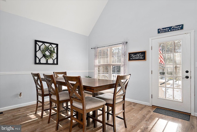 dining area featuring high vaulted ceiling, a healthy amount of sunlight, and hardwood / wood-style flooring