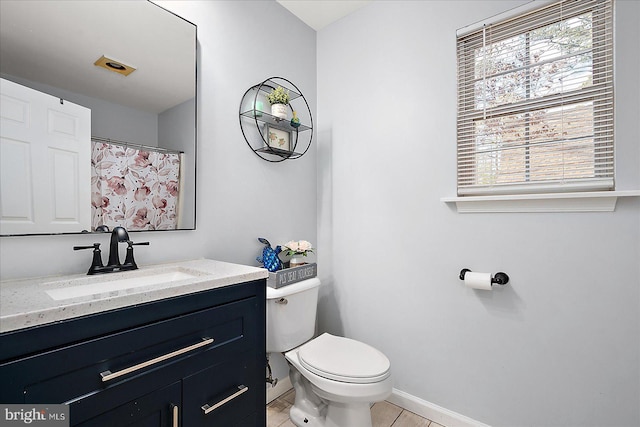 bathroom with toilet, vanity, and tile patterned flooring