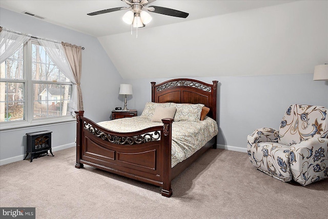 carpeted bedroom featuring ceiling fan, a wood stove, and lofted ceiling