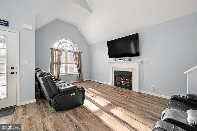 living room featuring vaulted ceiling, a fireplace, and hardwood / wood-style flooring