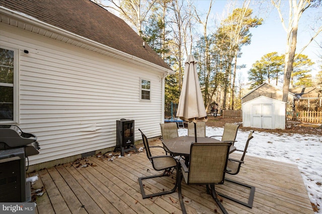 snow covered deck with a grill and a storage unit