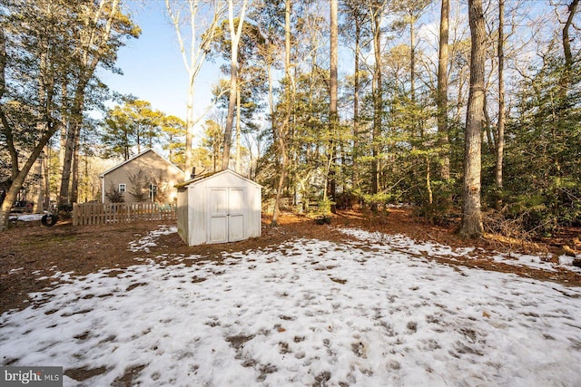 snowy yard featuring a storage shed