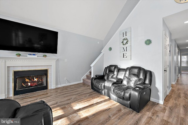 living room with lofted ceiling, a fireplace, and hardwood / wood-style flooring