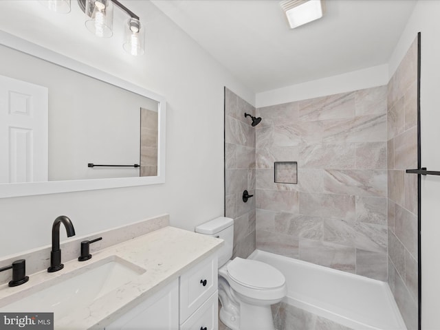 bathroom with vanity, toilet, and a tile shower