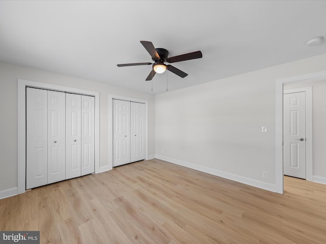 unfurnished bedroom featuring multiple closets, light hardwood / wood-style floors, and ceiling fan