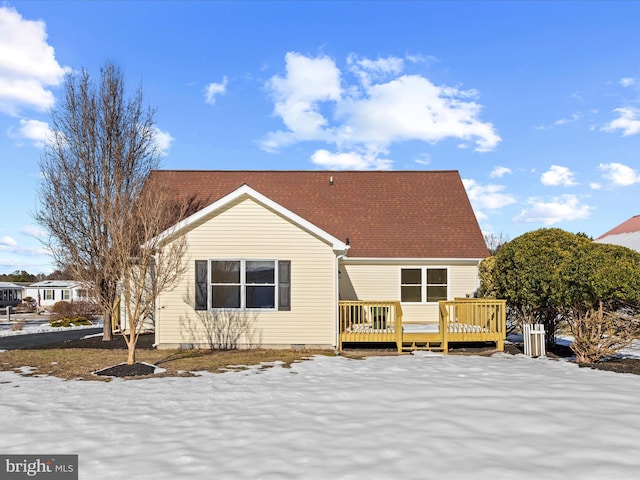 snow covered back of property with a wooden deck