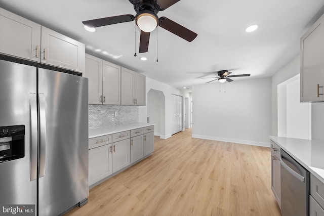 kitchen featuring appliances with stainless steel finishes, gray cabinetry, backsplash, and light hardwood / wood-style flooring