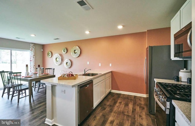 kitchen with appliances with stainless steel finishes, dark hardwood / wood-style flooring, white cabinets, and sink