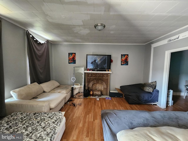 living room featuring hardwood / wood-style flooring, ornamental molding, and a fireplace