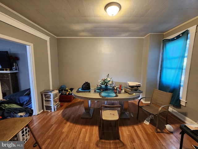 dining area featuring a brick fireplace, crown molding, and hardwood / wood-style floors