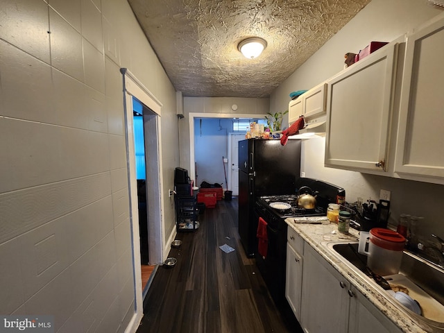 kitchen featuring white cabinets, black range, a textured ceiling, dark wood-type flooring, and sink