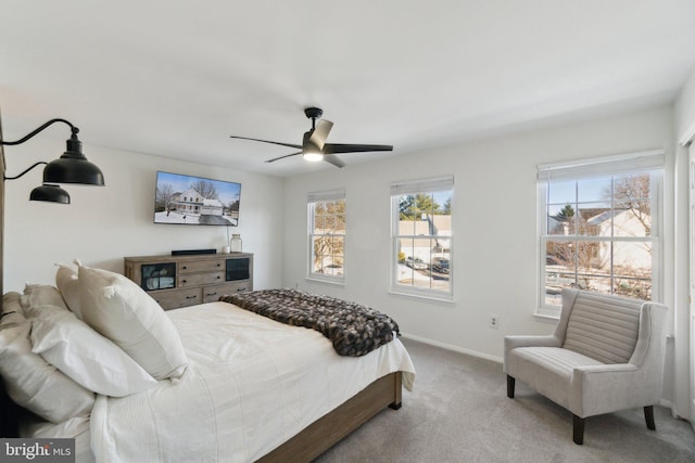 bedroom with multiple windows, ceiling fan, and light colored carpet