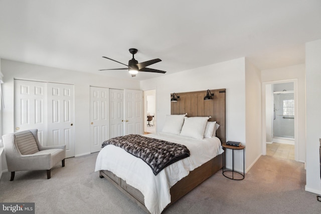 bedroom with ensuite bath, ceiling fan, light carpet, and multiple closets