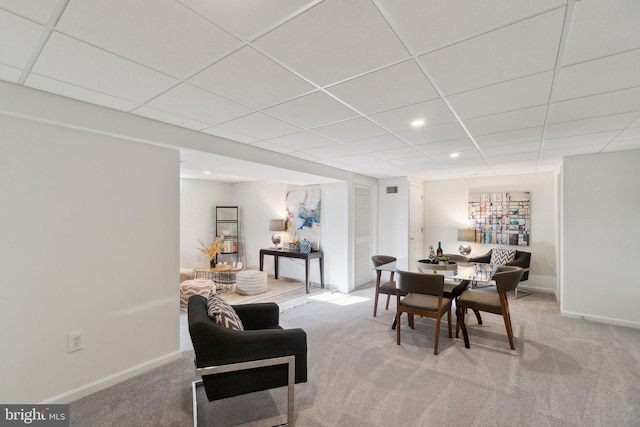 carpeted dining area featuring a paneled ceiling