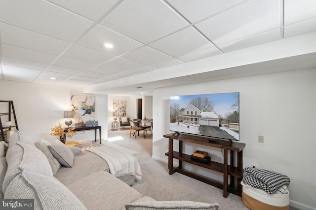 carpeted living room featuring a drop ceiling