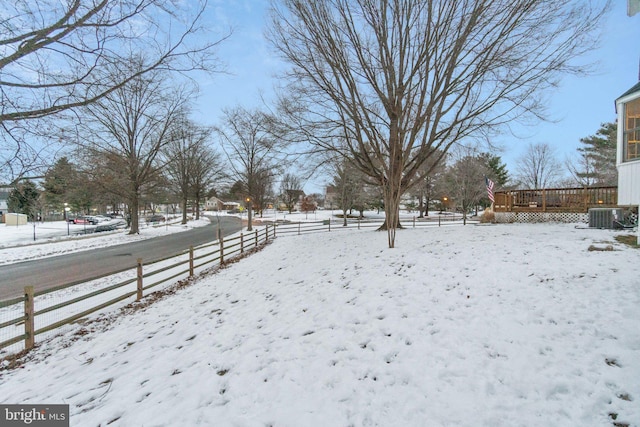 yard layered in snow with central air condition unit and a wooden deck