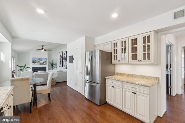 kitchen featuring light stone countertops, dark hardwood / wood-style floors, stainless steel refrigerator with ice dispenser, white cabinets, and ceiling fan