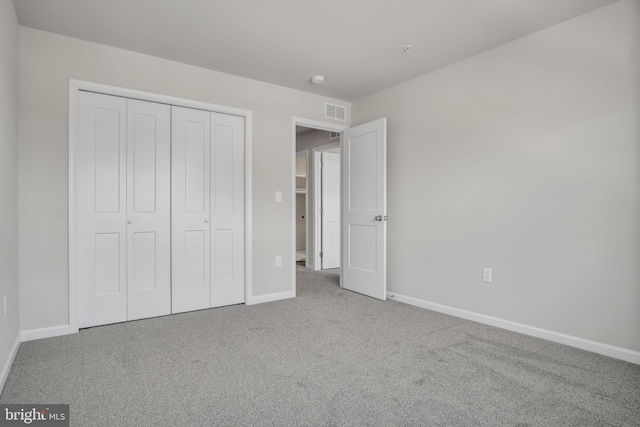 unfurnished bedroom featuring carpet floors, a closet, visible vents, and baseboards