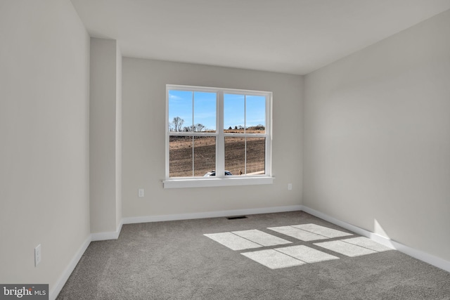 carpeted spare room with visible vents and baseboards