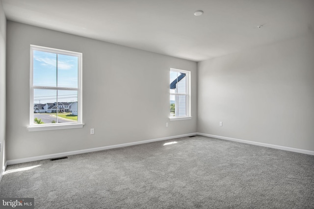 unfurnished room featuring carpet flooring, visible vents, and baseboards