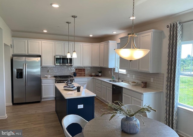 kitchen with stainless steel appliances, hanging light fixtures, a center island, sink, and white cabinetry