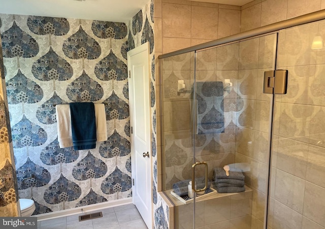 bathroom featuring toilet, a shower with door, and tile patterned floors